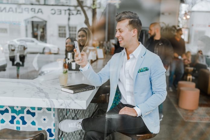 Mann, der ein mobiles Gerät in einem Restaurant verwendet
